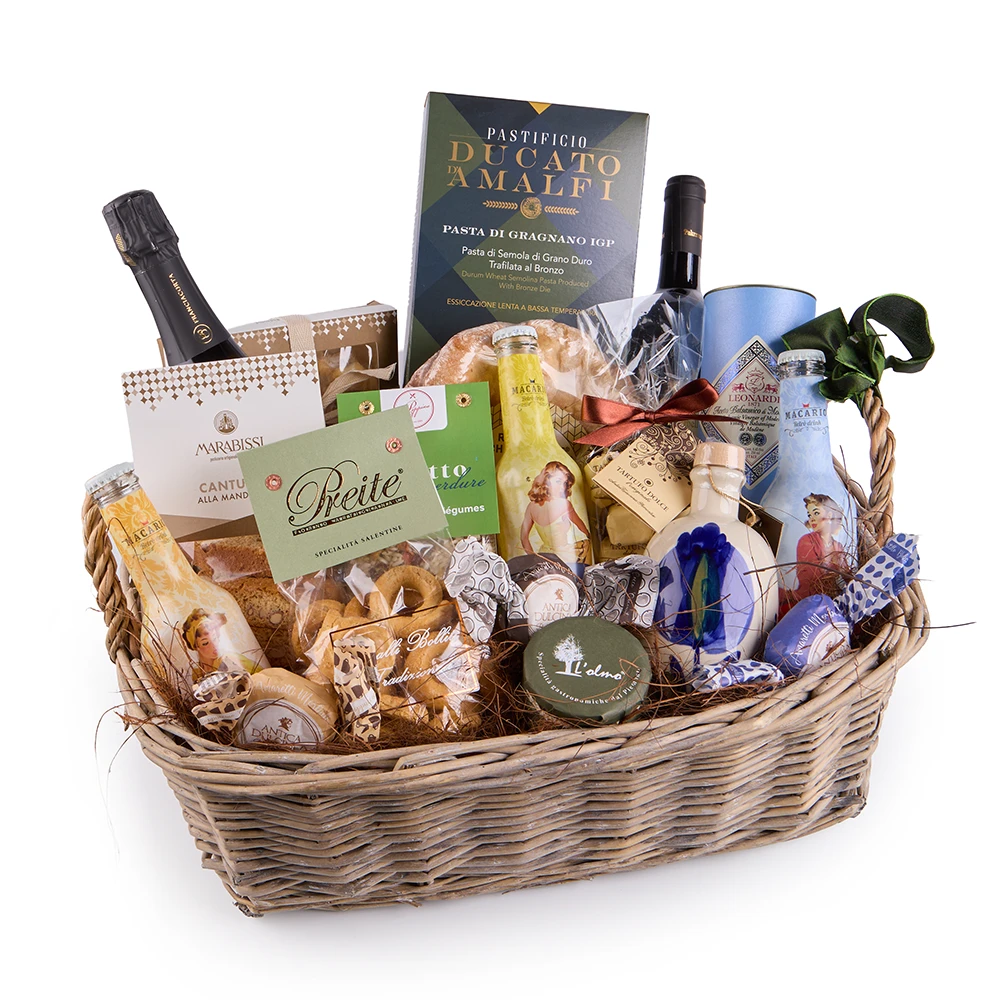 Italienischer Feinkost Geschenkkorb mit Pasta, Olivenöl, Wein, Süßwaren und mediterranen Delikatessen in einem geflochtenen Korb auf rustikalem Holztisch