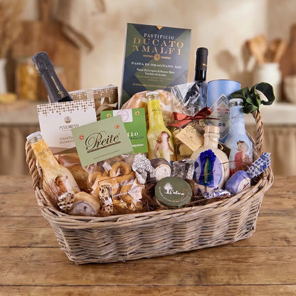 Italienischer Feinkost Geschenkkorb mit Pasta, Olivenöl, Wein, Süßwaren und mediterranen Delikatessen in einem geflochtenen Korb auf rustikalem Holztisch